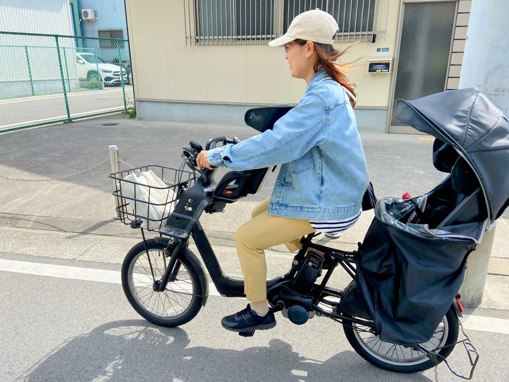 前後に子ども乗せシートが付いた電動自転車に乗る女性