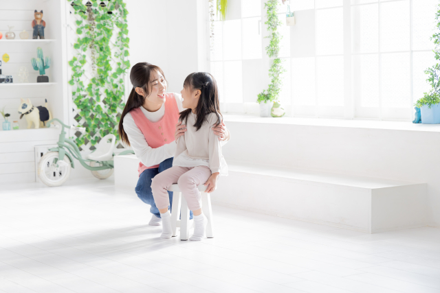 保育士さんが子どもと目線を合わせて話している（保育園のイメージ）