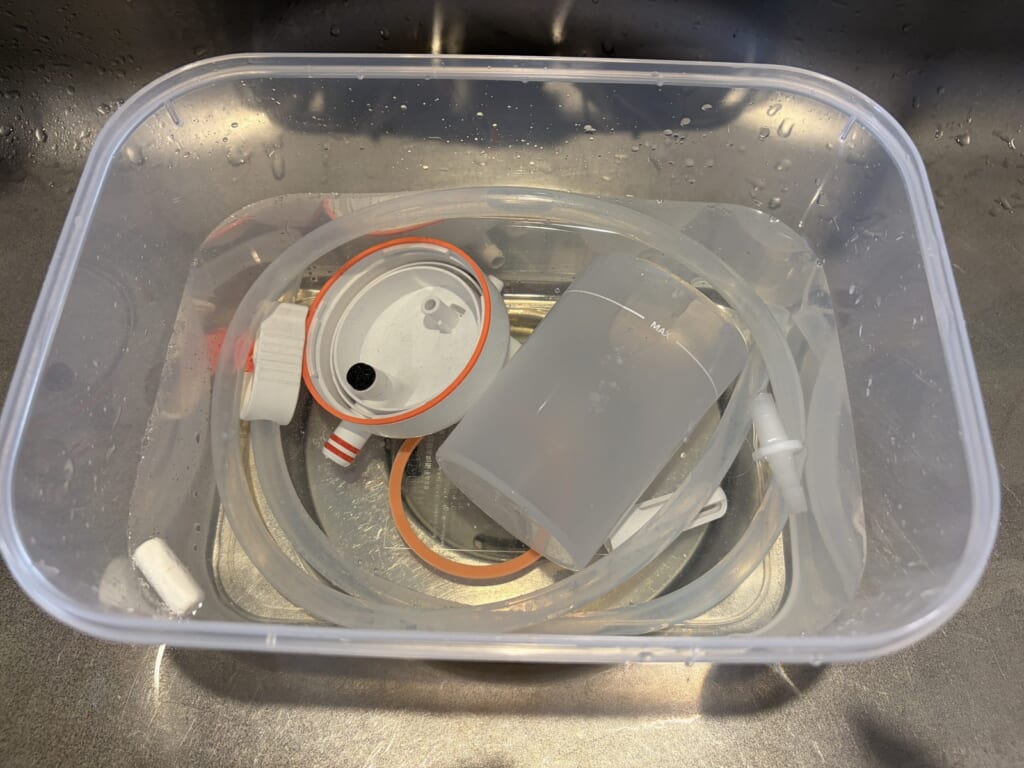 キッチンハイターを薄めた液にメルシーポットの部品を浸け置きしているところ